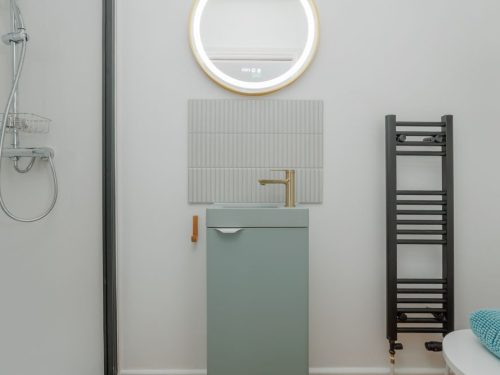Bathroom sink and mirror with gold rim at Beachway House holiday cottage