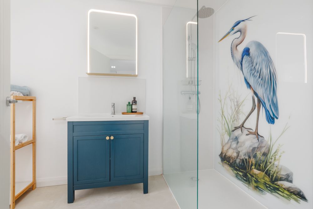 Bathroom with shower screen, sink, and blue cabinet